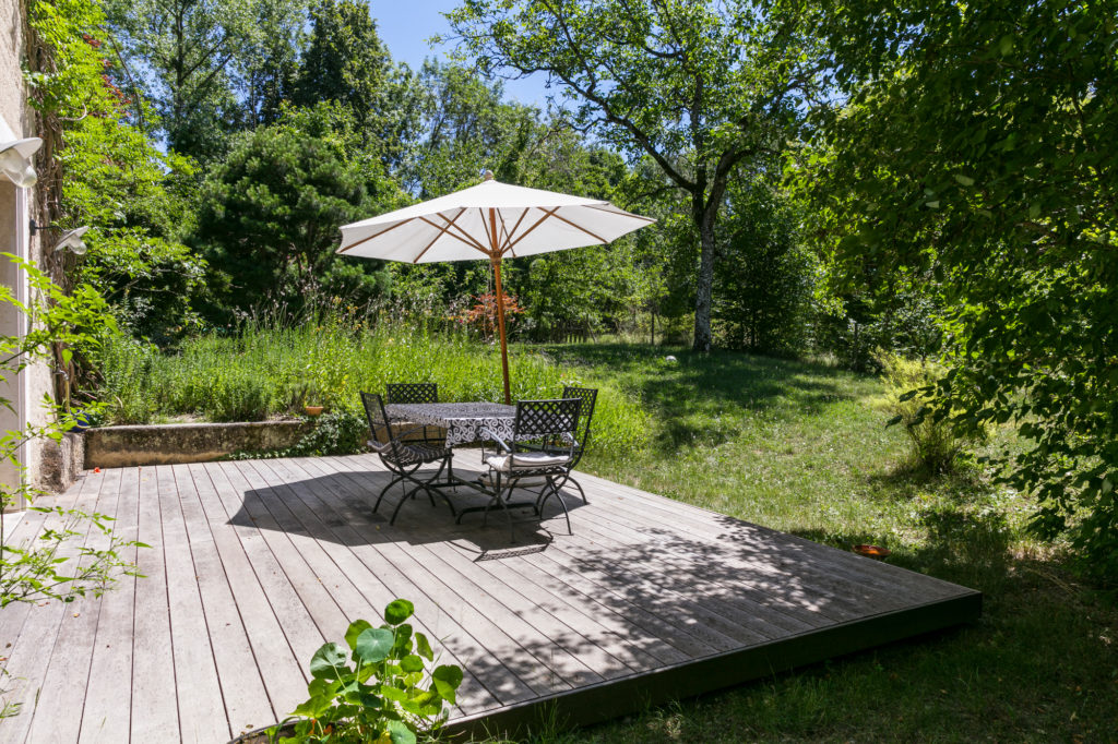 terrasse en bois avec parasol beige. table et chaises en bois