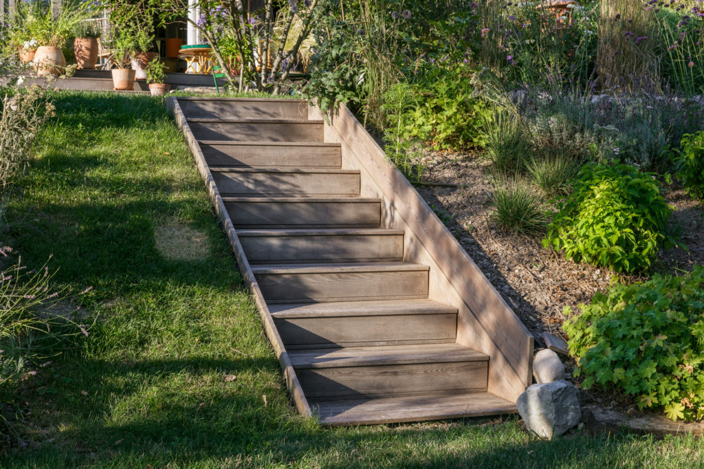 Escalier en bois dans un jardin avec du gazon et des plantes vertes
